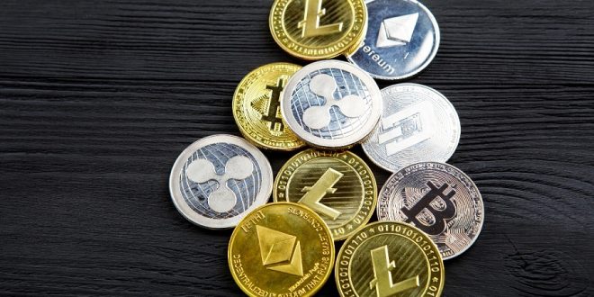 Silver and golden coins with bitcoin, ripple and ethereum symbol on wood background.