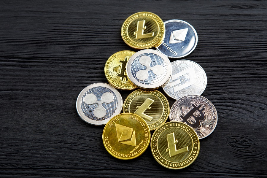 Silver and golden coins with bitcoin, ripple and ethereum symbol on wood background.